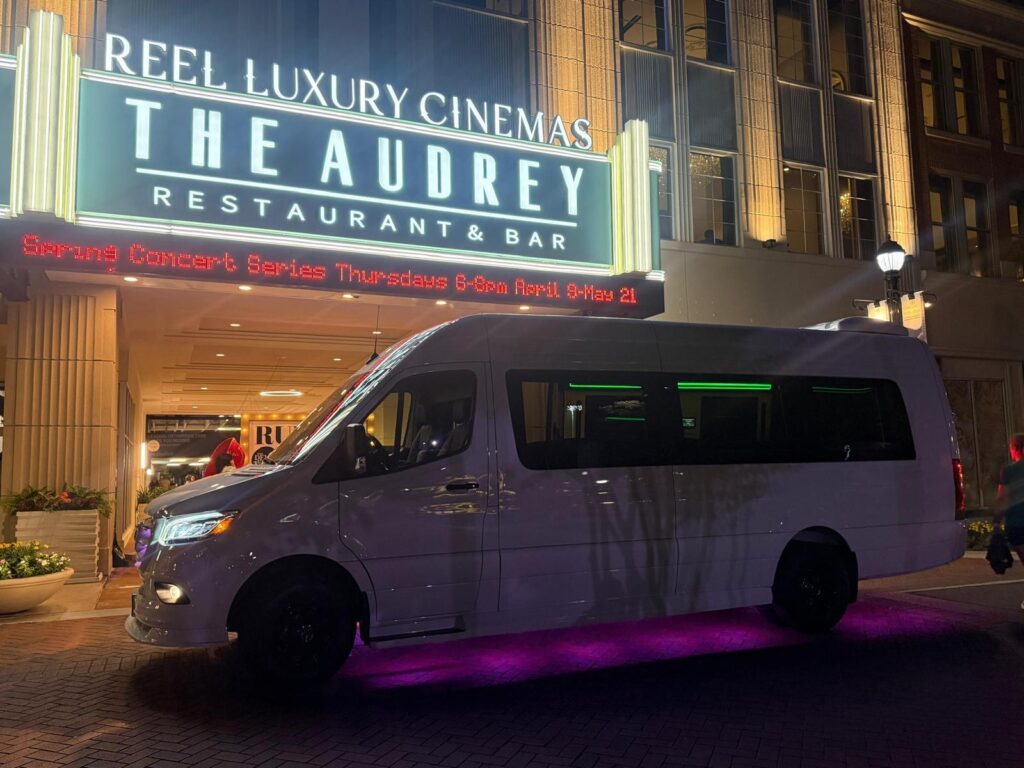 Side view of Deluxe white Sprinter limousine with purple accent lighting